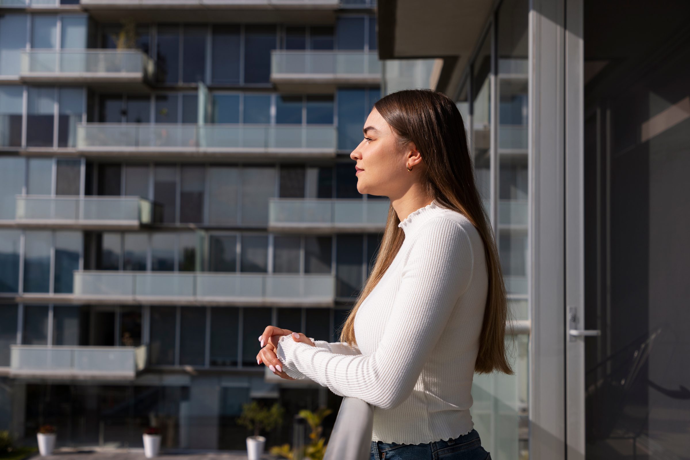 Mulher observando a cidade da varanda de um apartamento